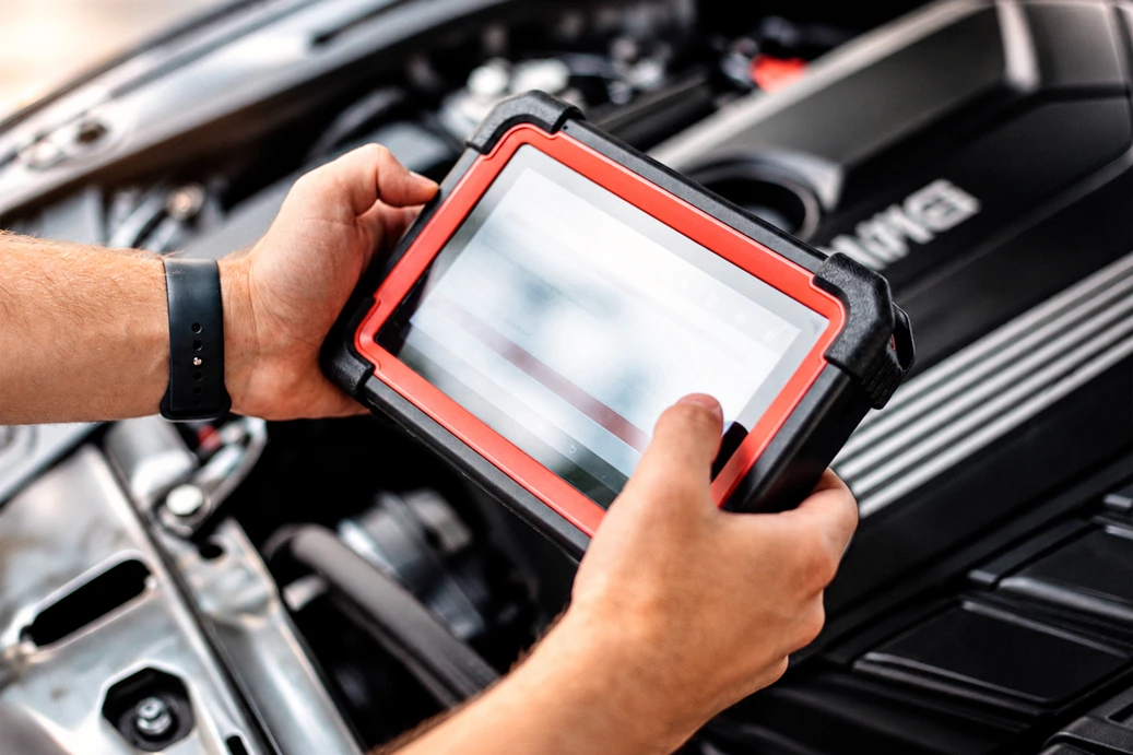 Técnico con escáner de diagnóstico sobre el motor durante la codificación del módulo de transmisión